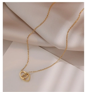 Détail macro du pendentif à double cœur entrelacé doré avec une chaîne fine