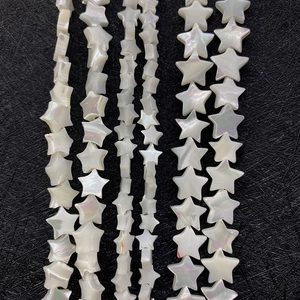 Vertical layout of star-shaped natural mother of pearl loose beads on a black textured surface