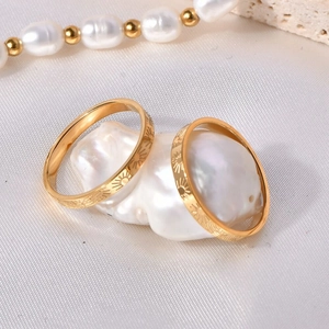 Minimalist gold sunflower engraved stainless steel rings on a white baroque pearl