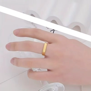 Close-up of a minimalist gold square signet ring worn by a model in a modern lifestyle setting
