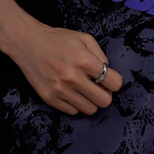 Polished silver Mobius twisted titanium steel ring worn on index finger in cool lighting