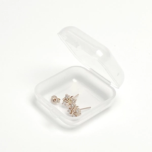 Boucles d'oreilles minimalistes en cristal argenté dans une boîte de rangement transparente