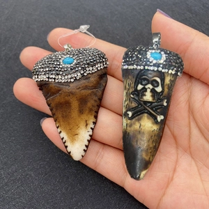Pendenti in resina a forma di punta di freccia e dente con strass e pietre blu in mano