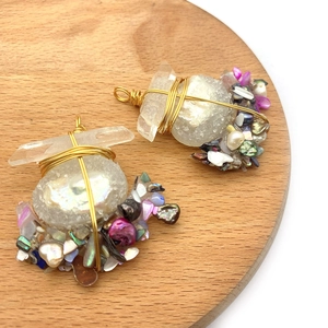 Close-up of handmade wire wrapped raw crystal pendants with pearls and shells on wood