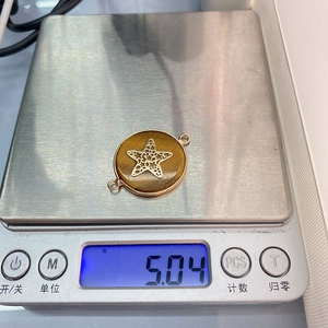 Macro detail of natural tiger eye stone pendant with gold edge and star on weighing scale