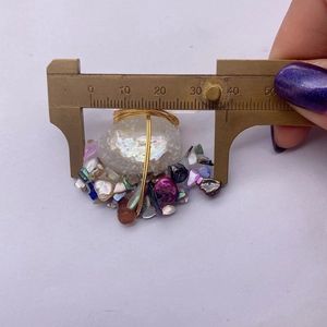 Measuring the handmade wire-wrapped crystal pearl pendant width with a brass caliper