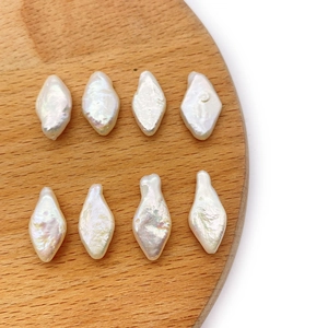 Macro view of 8 baroque irregular diamond-shaped freshwater pearls on a wooden tray