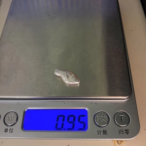 Baroque keshi pearl weighing 0.95g on a digital scale showing its natural silver luster