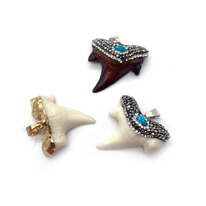 Dettaglio di ciondoli a dente di squalo stile boho con strass e finiture in foglia d'oro