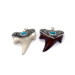Dettaglio dei ciondoli a dente di squalo in stile tribal con strass e pietra turchese
