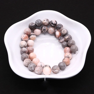 Macro shot of natural pink zebra stone beads for DIY jewelry making in a white ceramic dish