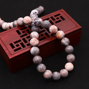 Natural pink zebra stone round beads on vintage wooden tray for DIY jewelry making