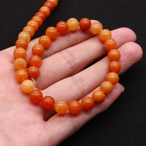 Detailed view of natural orange aventurine stone beads held in hand for sizing