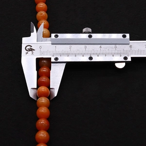 Macro shot measuring 8mm natural red aventurine round gemstone bead with a metal caliper