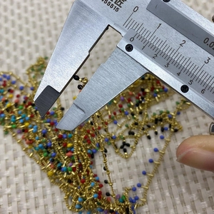 Close-up measurement of colorful beaded copper chain with calipers for DIY jewelry