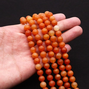 Polished natural carnelian agate beads 8mm to 10mm held in hand for jewelry making