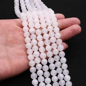 Hand holding polished translucent natural white jade round beads for DIY jewelry making