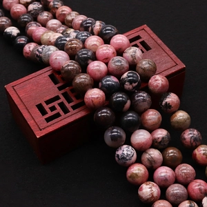 Perles en rhodochrosite naturelle polie avec motifs roses sur une boîte en bois vintage