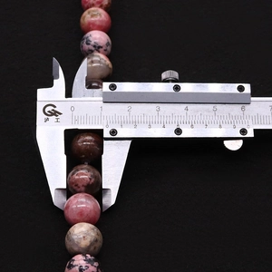 Détail de perles roses de 10mm mesurées avec un pied à coulisse numérique de précision