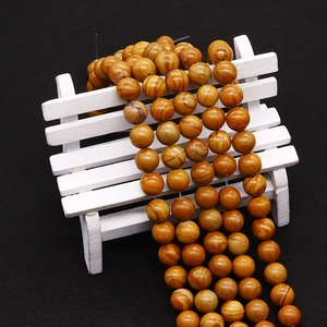 Perles en pierre à grain de bois jaune naturel pour bijoux DIY sur support blanc