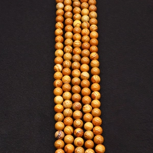 Détail macro de perles rondes en pierre naturelle veinée de bois avec trous percés
