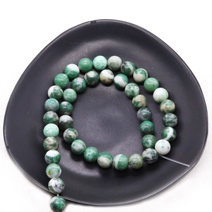 Polierte grüne und weiße Natursteinperlen in einer schwarzen Schale für DIY-Schmuck