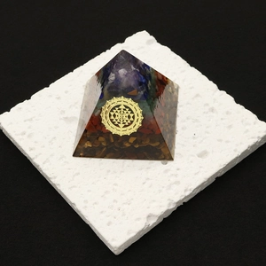 Orgonite pyramid with layered tiger eye stones and golden Sri Yantra symbol on a stand