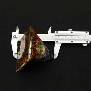 Measuring the base of a pyramid energy ornament with natural stone chips using a caliper