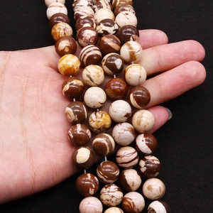 Handheld view of natural brown zebra stone round beads with polished striped texture