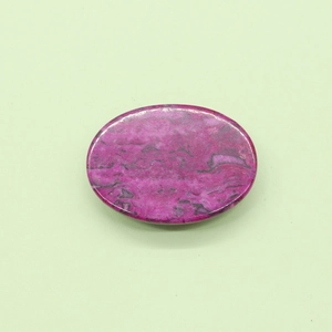 Dettaglio macro di pietra naturale ovale fucsia con venature nere e finitura lucida