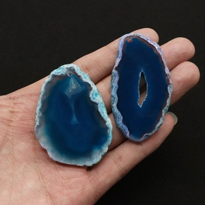 Dettaglio di due ciondoli in agata blu naturale con texture uniche e fori pre-perforati