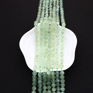 Vista dettagliata di perle di prenite verde chiaro con inclusioni nere naturali