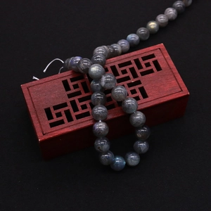Macro shot of polished labradorite beads with blue flash on decorative wooden box