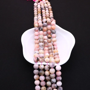 Detailed view of polished 6-10mm natural pink stone beads with unique mineral textures
