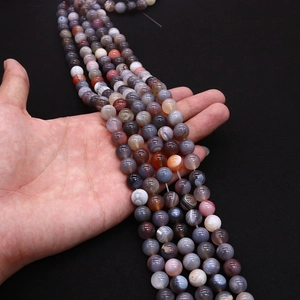 Detailed view of hand-held natural Persian agate beads with unique circular stripe patterns
