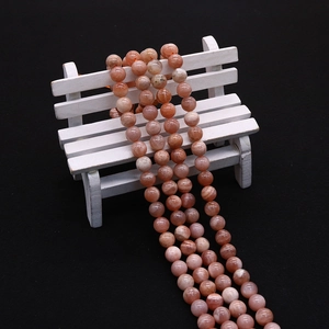 Close-up of natural orange sunstone beads showing texture and gloss on a black background