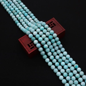 Macro detail of natural light blue amazonite gemstone beads on a vintage wooden stand