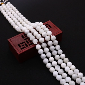 Macro shot of natural white moonstone round beads on a traditional red wooden box