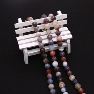 Close-up of polished natural Persian agate beads with silk textures on a white bench