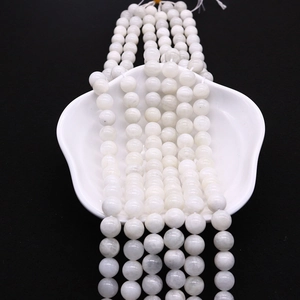 Detailed view of polished natural moonstone round beads on a white ceramic tray