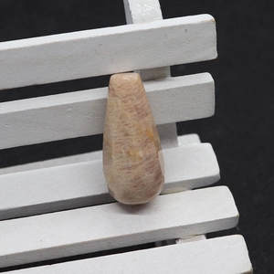 Macro shot of polished teardrop-shaped orange moonstone pendant with natural textures