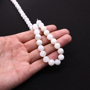 Macro shot of 8mm white moonstone beads string held by hand showing smooth texture