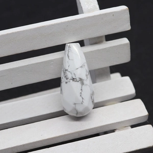 Macro detail of faceted white howlite teardrop stone bead with natural grey marble texture