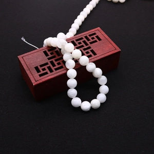 Detailed view of polished natural white moonstone round beads on traditional red box
