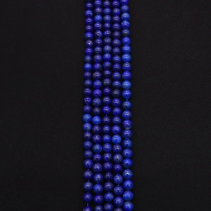 Macro shot of natural deep blue lapis lazuli round beads with gold pyrite flecks