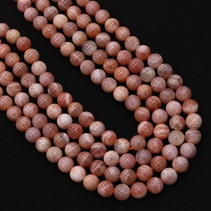 Polished natural orange sunstone round beads for DIY jewelry making on black background