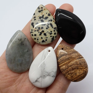 Five assorted teardrop-shaped natural stone pendants for DIY jewelry making held in hand