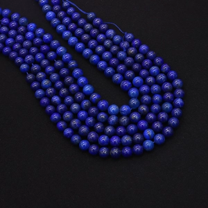 Macro shot of natural lapis lazuli round beads with gold pyrite flecks on black surface