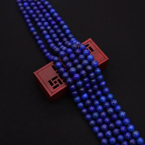 Macro detail of natural lapis lazuli round beads with gold pyrite flecks on black surface