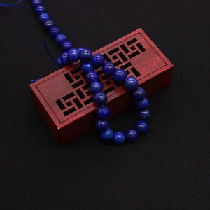 Detailed shot of dark blue lapis lazuli round beads with natural pyrite on a wooden box